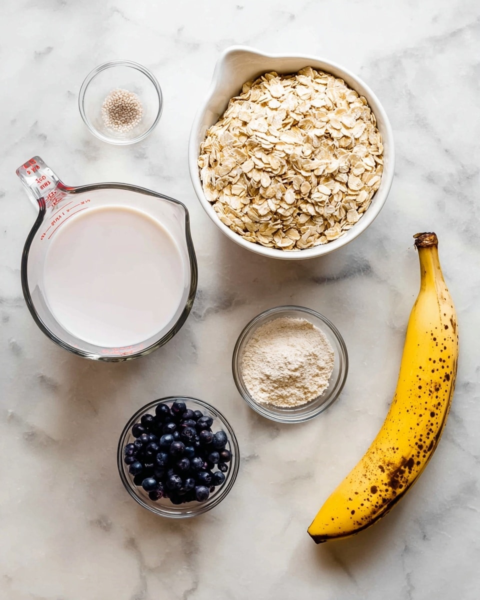 The image shows six ingredients placed on a white marbled surface: a clear measuring cup with white liquid on the left, a white metal measuring cup filled with light brown rolled oats on the top right, a small clear glass bowl with white powder to the right of the oats, a ripe yellow banana with brown spots laying curved on the bottom right, a small clear glass bowl with light brown powder below the measuring cup, and a white metal measuring cup filled with small dark blue berries positioned next to the banana. The colors contrast clearly against the white marbled surface, giving a fresh and clean look. photo taken with an iphone --ar 4:5 --v 7