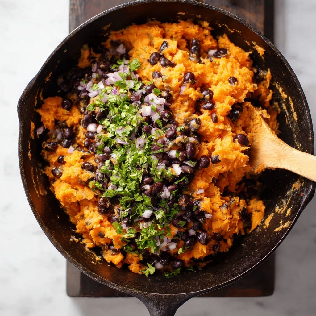 This image shows a close-up of a black cast iron skillet filled with a mixture of mashed orange sweet potatoes, whole black beans, and finely chopped translucent onions. On top of this mixture, there is a fresh pile of bright green chopped herbs, likely cilantro, adding a fresh contrast to the warm colors beneath. A wooden spoon is partially visible on the right side of the skillet, slightly stirring the ingredients. The skillet is placed on a white marbled surface, highlighting the vibrant colors of the food. photo taken with an iphone --ar 4:5 --v 7