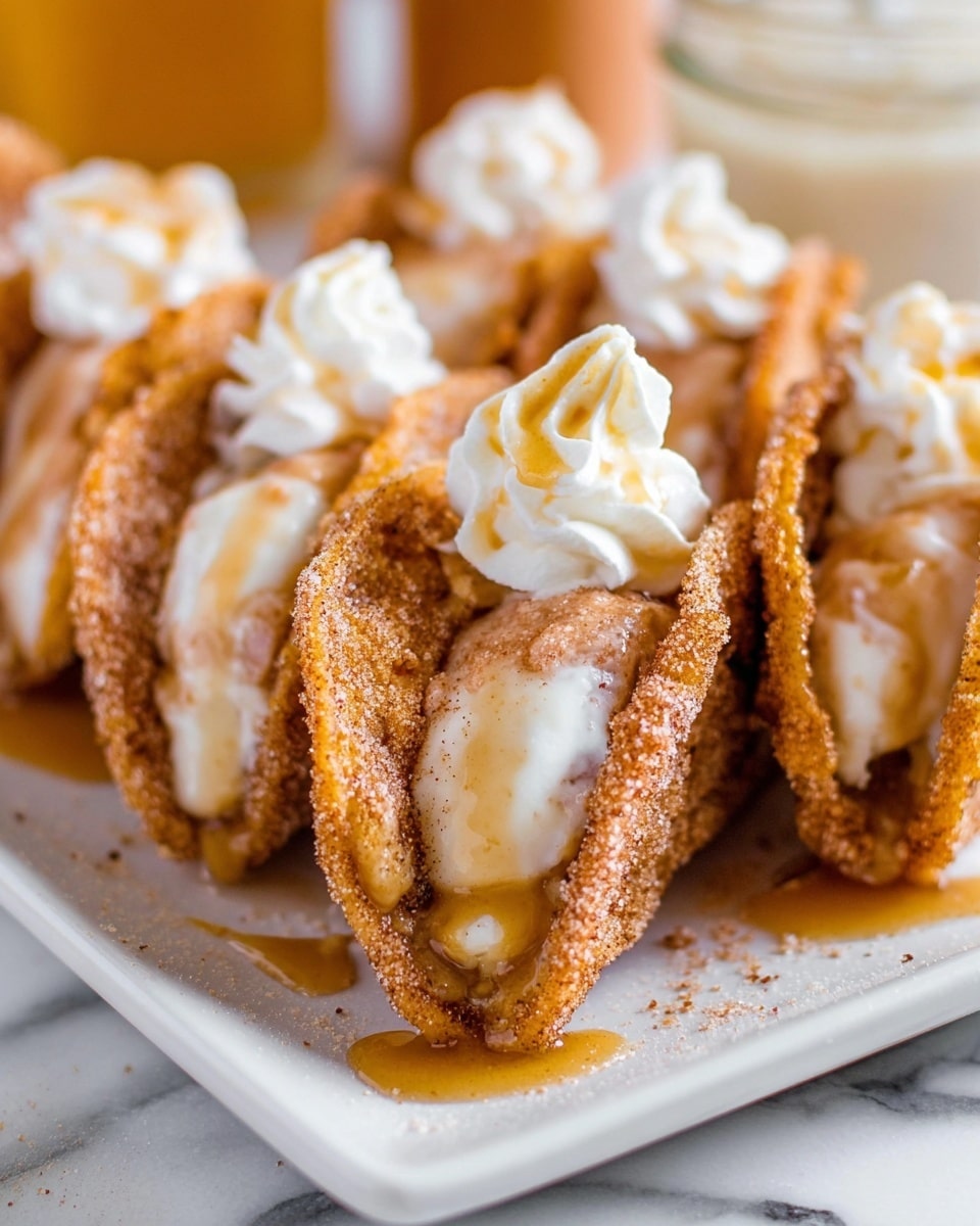 The image shows a close-up of several taco-shaped desserts arranged on a white rectangular plate. Each taco shell is golden brown and textured, coated with cinnamon sugar. Inside, there is a creamy white layer that looks smooth and thick, topped with a light brown cinnamon sauce that drips slightly over the edges. On top of the creamy filling, there is a dollop of fluffy white whipped topping with a small drizzle of golden syrup. The background surface is a white marbled texture, with a blurred jar in the upper right corner. Photo taken with an iphone --ar 4:5 --v 7