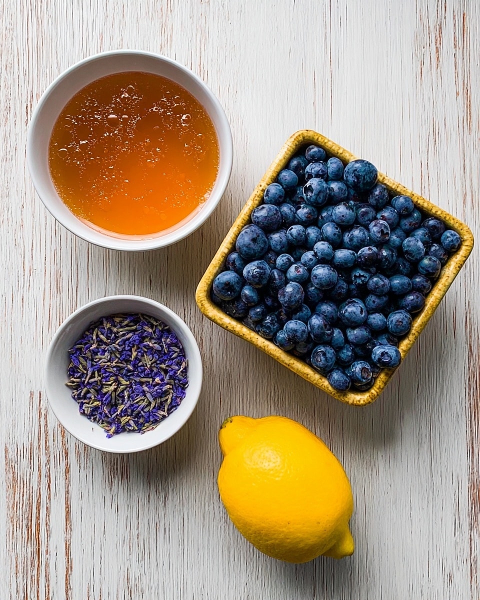The image shows four main items placed on a white marbled textured surface. On the top right, there is a square basket filled with many small, round, and dark blue blueberries with a slightly frosted look, tightly packed together. To the left of the basket, there is a white bowl filled with an orange-brown liquid that looks smooth with some small bubbles on the surface. Below this bowl, there is another white bowl holding small, purple dried flower petals scattered neatly inside. On the bottom right of the image, there is a bright yellow lemon with a smooth skin and no visible blemishes. The overall setting is clean and brightly lit, with the natural colors of the items standing out clearly. Photo taken with an iphone --ar 4:5 --v 7
