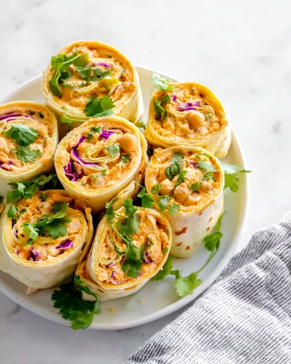A close-up view of several tortilla wraps cut into small rounds, stacked together on a white plate; each wrap has three visible layers—an outer soft beige tortilla, a thick middle spread of orange-colored filling with a smooth texture, and an inner layer containing small pieces of green leafy vegetables and purple cabbage, with slight hints of red and white bits mixed in. The presentation shows the rolls tightly packed, revealing spiraled layers of filling and vegetables inside. The background is a white marbled texture. photo taken with an iphone --ar 4:5 --v 7