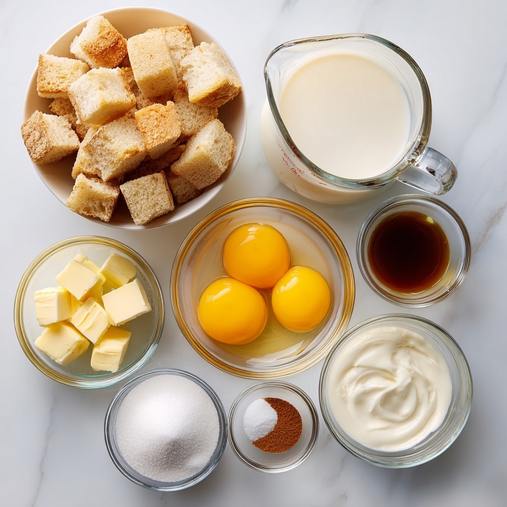 A top view shows several small glass bowls arranged on a white marbled surface. The largest bowl contains light golden brown cubes of french bread with a rough texture. To its right, a clear glass measuring cup is filled with smooth white milk. Below the bread bowl, a medium glass bowl holds five bright yellow egg yolks mixed with clear egg whites. Next to it, a small bowl holds pale yellow butter chunks. There is also a bowl of white half & half cream, another small bowl with vanilla extract showing a dark brown liquid, a tiny bowl of white salt, a small bowl of ground cinnamon with a dark reddish-brown color, and a glass bowl filled with fine white sugar. Each ingredient is clearly visible against the clean white marbled surface. Photo taken with an iphone --ar 4:5 --v 7