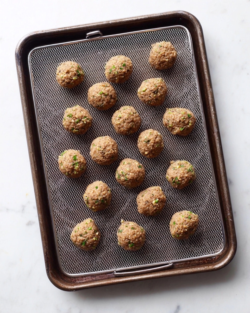 The image shows several round meatballs covered in a shiny dark brown sauce with visible small bits of nuts or vegetables inside, all sitting in a white pan filled with thick sauce. The meatballs have a moist, textured surface with some steam rising from them, making them look hot and fresh. The background is a white marbled texture. photo taken with an iphone --ar 4:5 --v 7