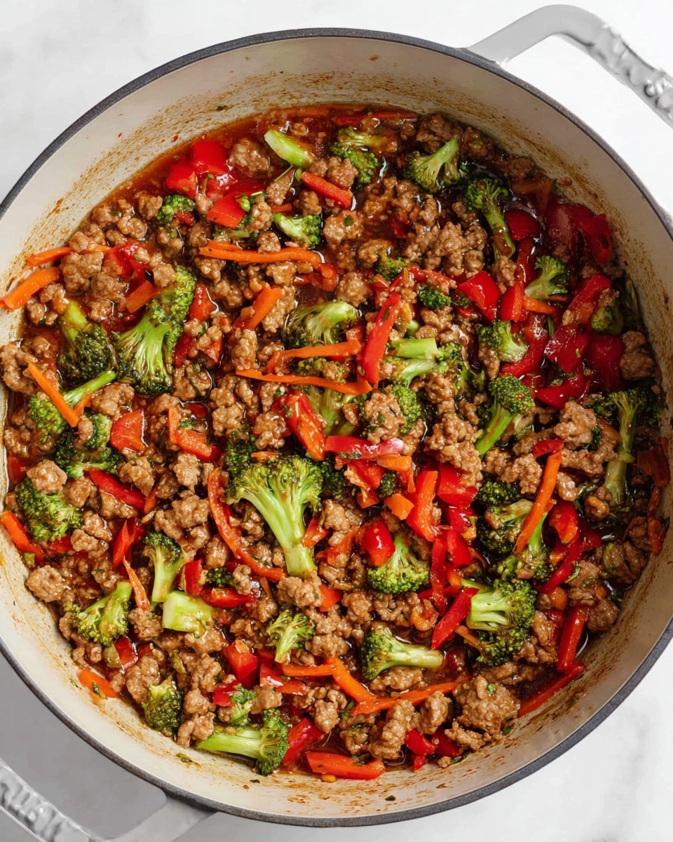 A large white cooking pot filled with a colorful mix of cooked ground meat, bright green broccoli pieces, red bell pepper chunks, and thin orange carrot strips, all mixed in a shiny brown sauce that coats every ingredient evenly. The vegetables and meat are well combined and spread throughout the pot, showing a mix of textures from soft to slightly crunchy. Small bits of sauce stick to the sides of the pot, hinting at the savory flavors within, placed on a white marbled surface photo taken with an iphone --ar 4:5 --v 7