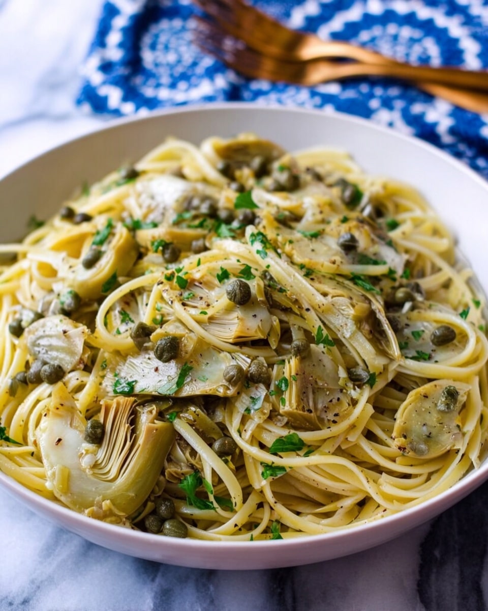 The dish shows a white bowl filled with long, pale yellow pasta strands tossed with soft, pale green and beige artichoke pieces that have a slightly glossy texture. Scattered on top are small, round, darker green capers and fresh parsley leaves adding specks of bright green. The whole pasta is lightly coated with a thin sauce that gives a slight shine and is speckled with ground black pepper. The bowl rests on a white marbled surface, and in the background, there is a blurred blue and white patterned cloth with wooden forks on it. Photo taken with an iphone --ar 4:5 --v 7