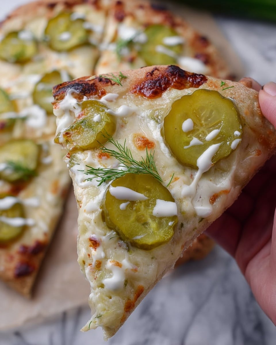 A close-up of a single slice of pizza held by a woman's hand shows three main layers: a pale golden crust at the bottom with a soft and slightly thick texture, a middle layer of creamy melted cheese with browned spots and an uneven bubbly surface, and a top layer featuring large pickles that are light green with a shiny, wet look. There are white drizzles of sauce and small thin green dill leaves scattered on the cheese and pickles. The background includes more blurred pizza slices on a white marbled surface, giving a fresh and homemade feel. photo taken with an iphone --ar 4:5 --v 7
