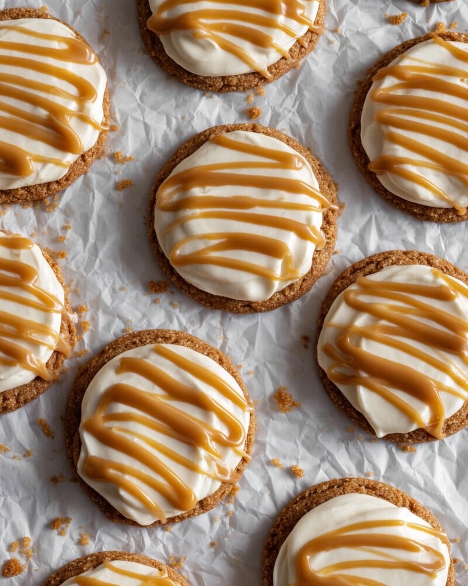 The image shows several round cookies arranged in rows on crinkled parchment paper over a white marbled surface. Each cookie has a golden-brown crumbly base layer topped with a thick, smooth layer of light cream-colored frosting. Over the frosting, there are drizzles of shiny caramel sauce in uneven stripes, adding a glossy, rich amber color on top. Some crumbs are scattered lightly around the cookies, emphasizing their crumbly texture. The arrangement is neat, and the view looks slightly from above, showing the full round shape of each cookie. photo taken with an iphone --ar 4:5 --v 7