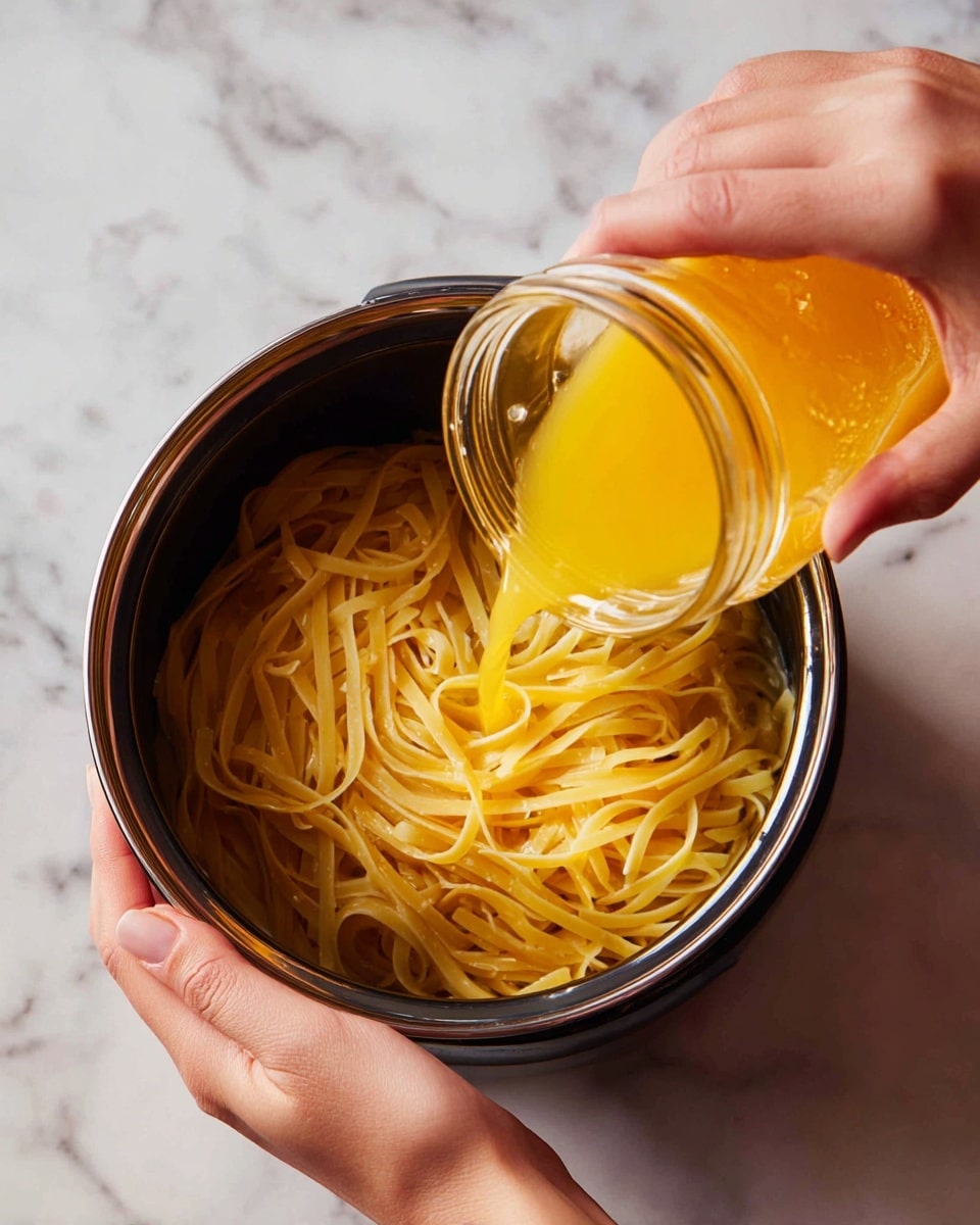 A woman’s hand is holding a clear jar, pouring orange liquid over a pot filled with dry, thin, yellow noodles. Another woman’s hand is steadying the pot, which is black with silver on top inside. The noodles are layered flat and long inside the pot. The pot is placed on a white marbled surface. Photo taken with an iphone --ar 4:5 --v 7