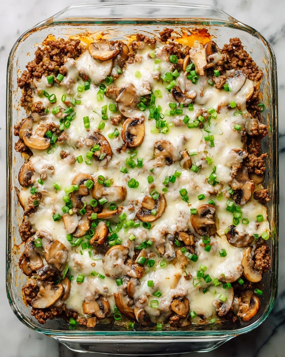 A clear glass square baking dish filled with a layered dish. The bottom layer consists of cooked brown ground meat mixed with sliced cooked mushrooms, both spread evenly. On top, there is a layer of melted white cheese, which is spotty and softly covering the meat and mushrooms. Finally, the dish is sprinkled with small, chopped green onions scattered all over. The baking dish is placed on a white marbled surface. Photo taken with an iphone --ar 4:5 --v 7