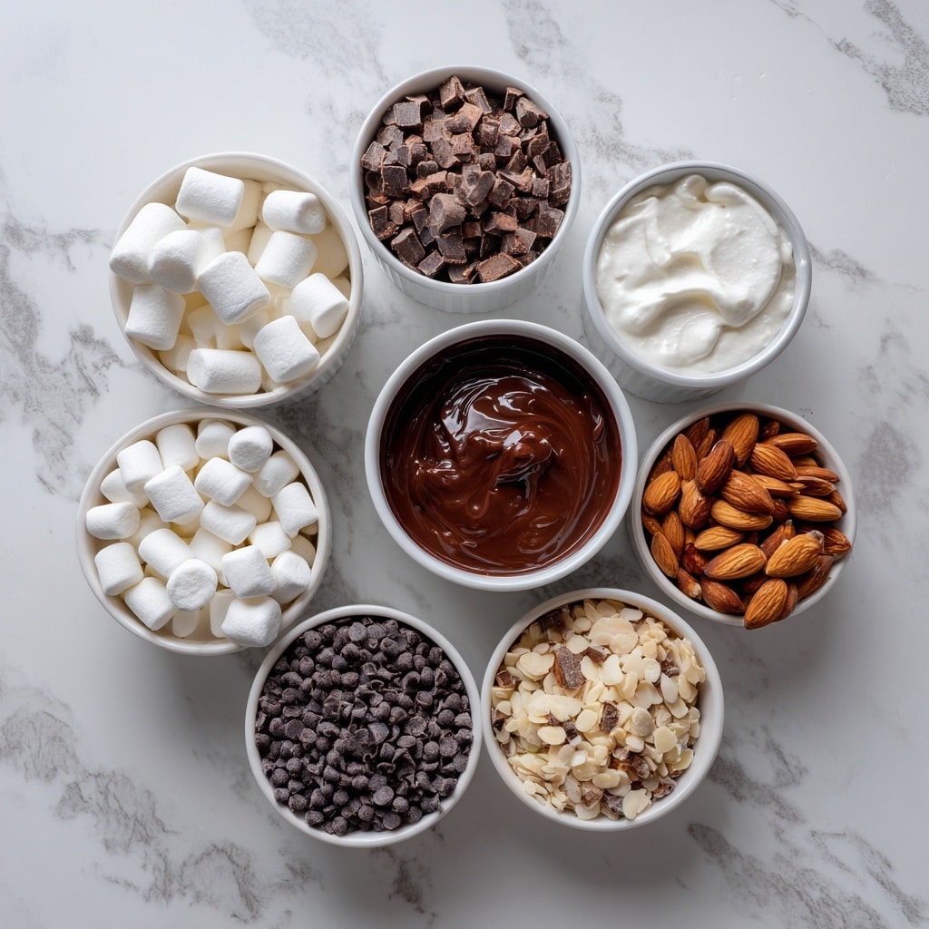 A yellow bowl with white zigzag patterns is filled with a thick, creamy chocolate mixture with small clumps, topped generously with small white marshmallows, dark mini chocolate chips, and pieces of chopped nuts, all piled high. The bowl is placed on a colorful polka dot coaster on a white marbled surface. In the background, there is a white ramekin filled with more chocolate chips and a white bowl filled with mini marshmallows, both slightly out of focus. Photo taken with an iphone --ar 4:5 --v 7