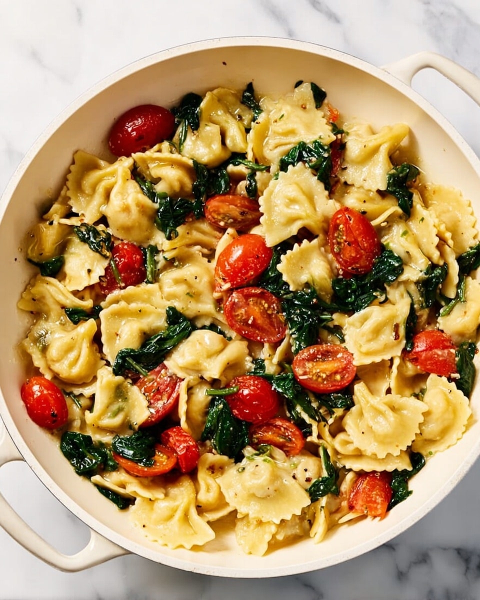 The dish is shown in a white pan filled with three main layers: the base layer is tender, pale yellow pasta with ruffled edges evenly spread out, mixed throughout are bright red cherry tomatoes, some whole and some slightly softened, and dark green spinach leaves that add a fresh, leafy texture. The dish is coated lightly with a glossy sauce, giving a slight shine to the pasta and vegetables. The background is a smooth, white marbled surface, making the colors of the dish stand out clearly. photo taken with an iphone --ar 4:5 --v 7