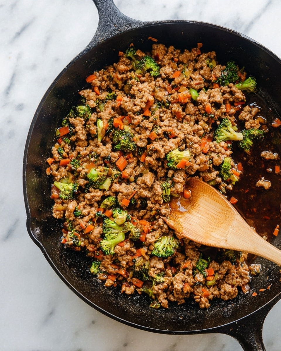 A black cast iron pan filled with cooked ground meat mixed with small bright green broccoli pieces and thin orange carrot strips in a dark brown sauce. The meat looks crumbly and moist, covering most of the pan. A wooden spoon is partially inside the pan, stirring the mixture, with some sauce pooling around the edges. The pan is set on a white marbled surface. Photo taken with an iphone --ar 4:5 --v 7