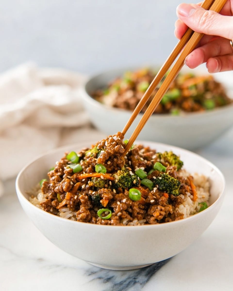 A white bowl filled with a base layer of light brown cooked rice topped with a thick layer of cooked ground meat mixed with small broccoli pieces and thin orange carrot strips, all coated in a brown sauce. The dish is garnished with small green onion pieces and sesame seeds. A woman's hand is using wooden chopsticks to pick up some of the meat mixture. Another similar bowl is shown blurred in the background on a white marbled surface. Photo taken with an iphone --ar 4:5 --v 7