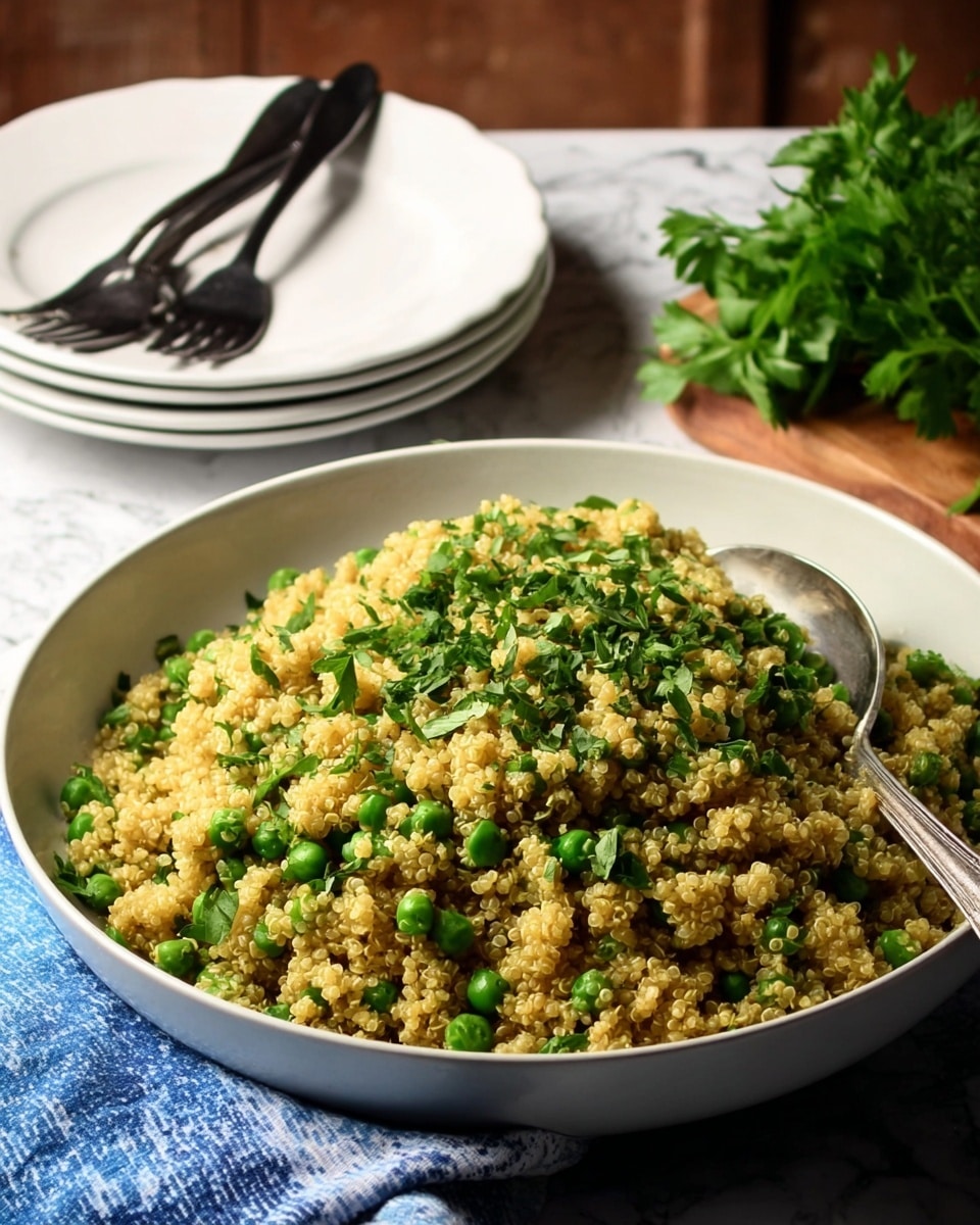 A large white bowl filled with a bright yellow quinoa salad mixed with small green peas, giving a speckled texture throughout. The quinoa grains are fluffy and separate, while the peas add a fresh touch of green. On top, there is a sprinkle of finely chopped green herbs that add a pop of color and freshness. A silver spoon rests on the right side inside the bowl, and beside the bowl is a blue and white striped cloth. The whole setting is placed on a white marbled surface. photo taken with an iphone --ar 4:5 --v 7