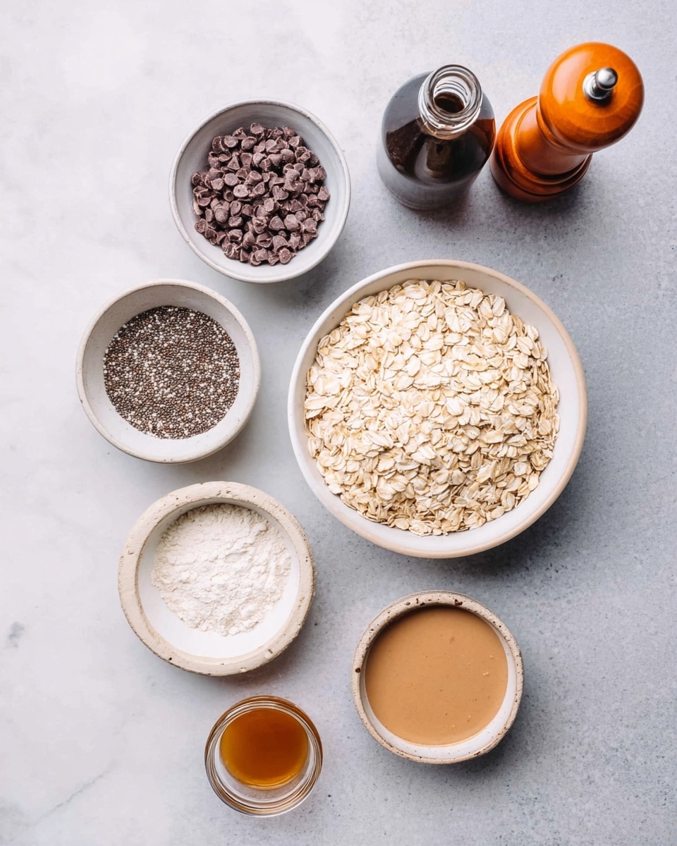 The image shows eight items arranged on a white marbled surface: one large white bowl filled with light beige rolled oats in the center, two medium white bowls above the oats with one containing small dark brown chocolate chips and the other filled with tiny black and white chia seeds, a small white bowl to the right with white flour, a small clear glass jar with amber liquid near the flour, a small round white bowl with light brown nut butter, a dark glass bottle with dark liquid behind the bowls, and an orange wooden pepper grinder on the far right. The colors mainly feature soft neutrals with a few dark and warm tones. Photo taken with an iphone --ar 4:5 --v 7