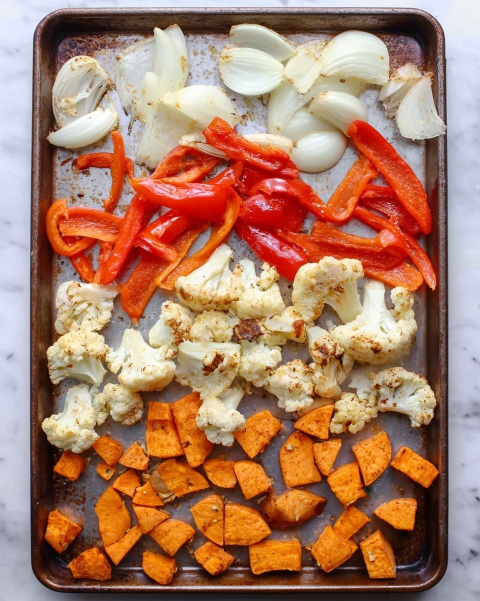 A baking tray with three layers of roasted vegetables arranged in sections: at the top, large white onion chunks mixed with long slices of bright red bell peppers; in the middle, light beige cauliflower florets with some light browning from roasting; at the bottom, several pieces of roasted orange sweet potato cut into small, uneven shapes. The tray rests on a white marbled surface. Photo taken with an iphone --ar 4:5 --v 7