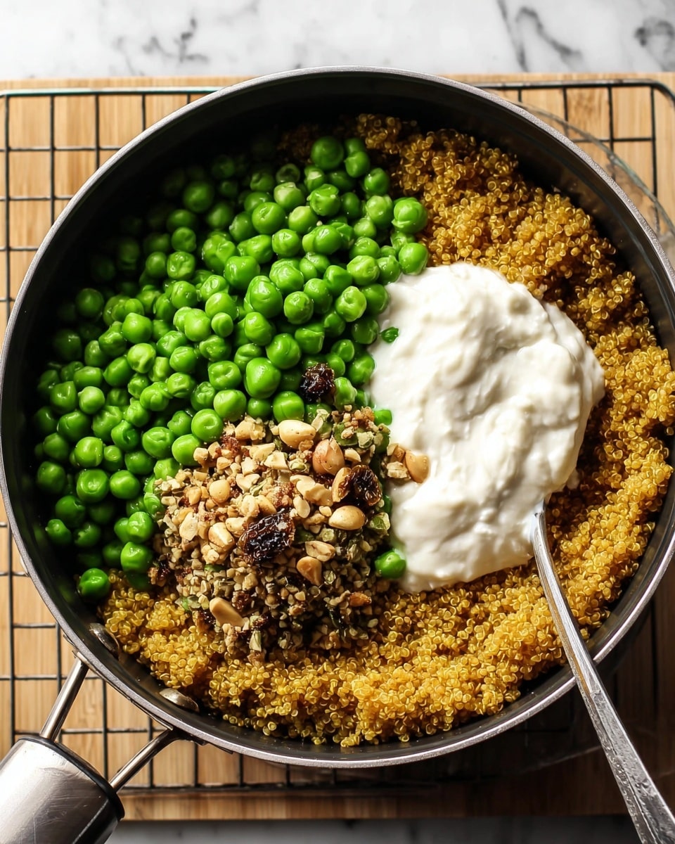 A black pot filled with three clear layers of food sitting on a metal cooling rack over a white marbled surface: the bottom layer is golden cooked quinoa covering the base, the middle layer is bright green peas piled mostly on one side, and the top has a dollop of white creamy yogurt next to a small mound of mixed nuts and seeds that are light brown with dark bits, with a silver spoon resting partly in the yogurt photo taken with an iphone --ar 4:5 --v 7