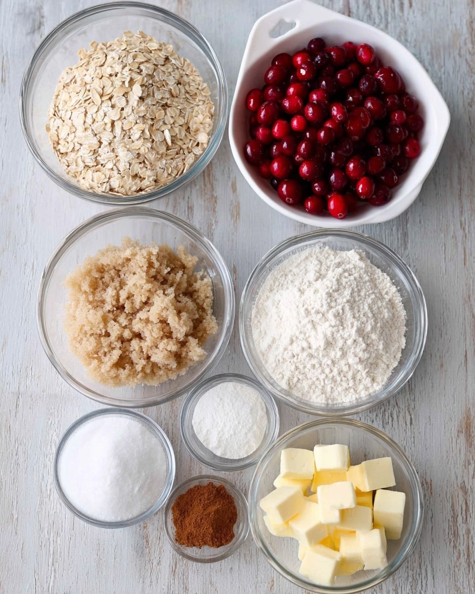 The image shows seven clear glass bowls and one white measuring cup arranged neatly on a white marbled surface. The top left bowl contains light beige rolled oats with a coarse texture. To its right, the white measuring cup is filled with bright red cranberries, some shiny and round. Below the oats, a bowl holds light brown sugar with a grainy texture. Next to it to the right, a bowl is filled with white flour, powdery and soft. Below these, a smaller bowl has white coarse salt, and another small bowl contains light brown ground cinnamon. There is also a tiny bowl with white baking powder. Finally, the bottom right bowl holds small cubes of pale yellow butter. photo taken with an iphone --ar 4:5 --v 7