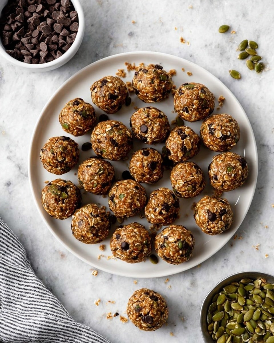 A round white plate filled with 25 small round energy balls made mainly of oats, some with chocolate chips and some with green pumpkin seeds, evenly spread in a neat pattern. Each ball is textured with visible oats, seeds, and chocolate, showing a mix of brown, dark brown, and green colors. One ball is placed just outside the plate at the bottom. To the top left, there is a white bowl with dark chocolate chips, and to the bottom right, a small silver bowl holds green pumpkin seeds with some seeds spilled gently on the white marbled surface, which covers the entire background. A striped cloth is partially visible at the bottom left. Photo taken with an iphone --ar 4:5 --v 7