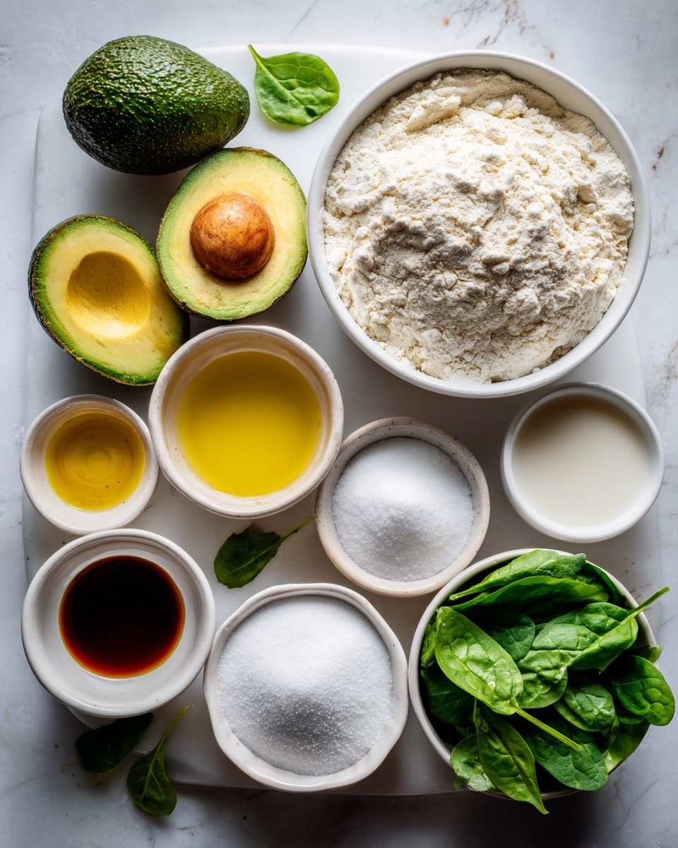 The image shows a flat lay of various ingredients on a white marbled surface. On the top right, there is a large bowl filled with white flour that has a slightly rough texture and some small clumps on the surface. Next to it is a small white bowl of dairy-free milk with a smooth, pale liquid. Below that is a white bowl with golden oil that has a shiny surface. Next to the oil, there is a small white bowl with dark brown vanilla extract that looks thick and glossy. Towards the bottom center is a tiny white bowl containing white baking powder and soda, looking powdery and fine. To the left of this is a medium white bowl filled with white sugar, showing a smooth, grainy texture. Above the sugar bowl, there is a small white bowl with pale yellow lemon juice, smooth and shiny. On the left side of the image, there are three avocados: one whole with rough dark green skin, one cut open showing bright green flesh and a brown pit, and one half with a hollow where the seed was removed. Below the avocados, there is a small white bowl with fresh baby spinach leaves that are bright green with a slightly glossy, wrinkled texture. The whole setting is bright with soft natural light. photo taken with an iphone --ar 4:5 --v 7