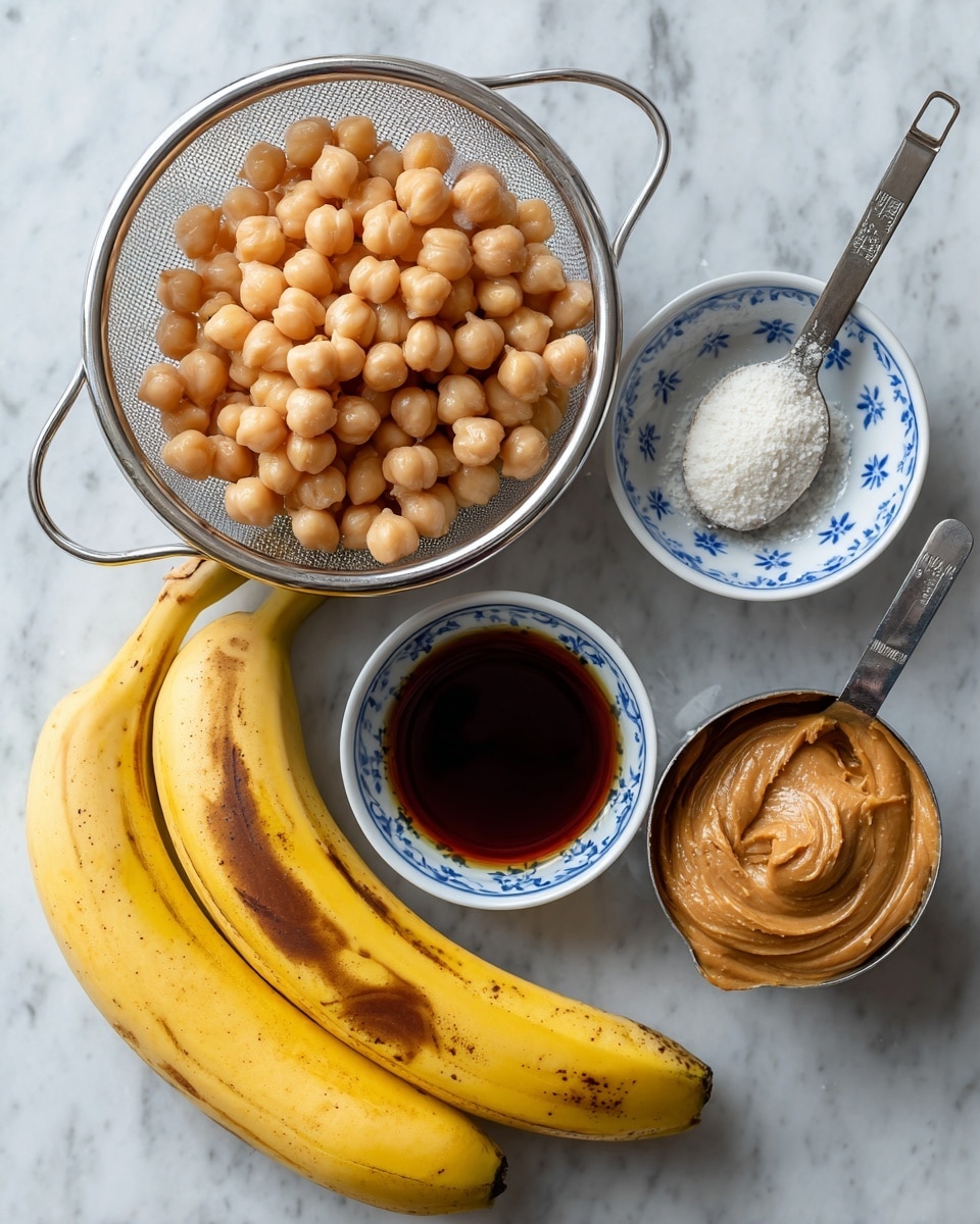 The image shows five main items arranged on a white marbled surface. At the top left, there is a metal strainer filled with light beige chickpeas. Below it, two ripe yellow bananas with brown spots rest side by side. To the right of the bananas, a metal measuring spoon holds dark vanilla extract. Above this, a white small dish with blue flower patterns contains white baking powder. At the top right, a roughly full metal measuring cup holds smooth light brown peanut butter. Photo taken with an iphone --ar 4:5 --v 7
