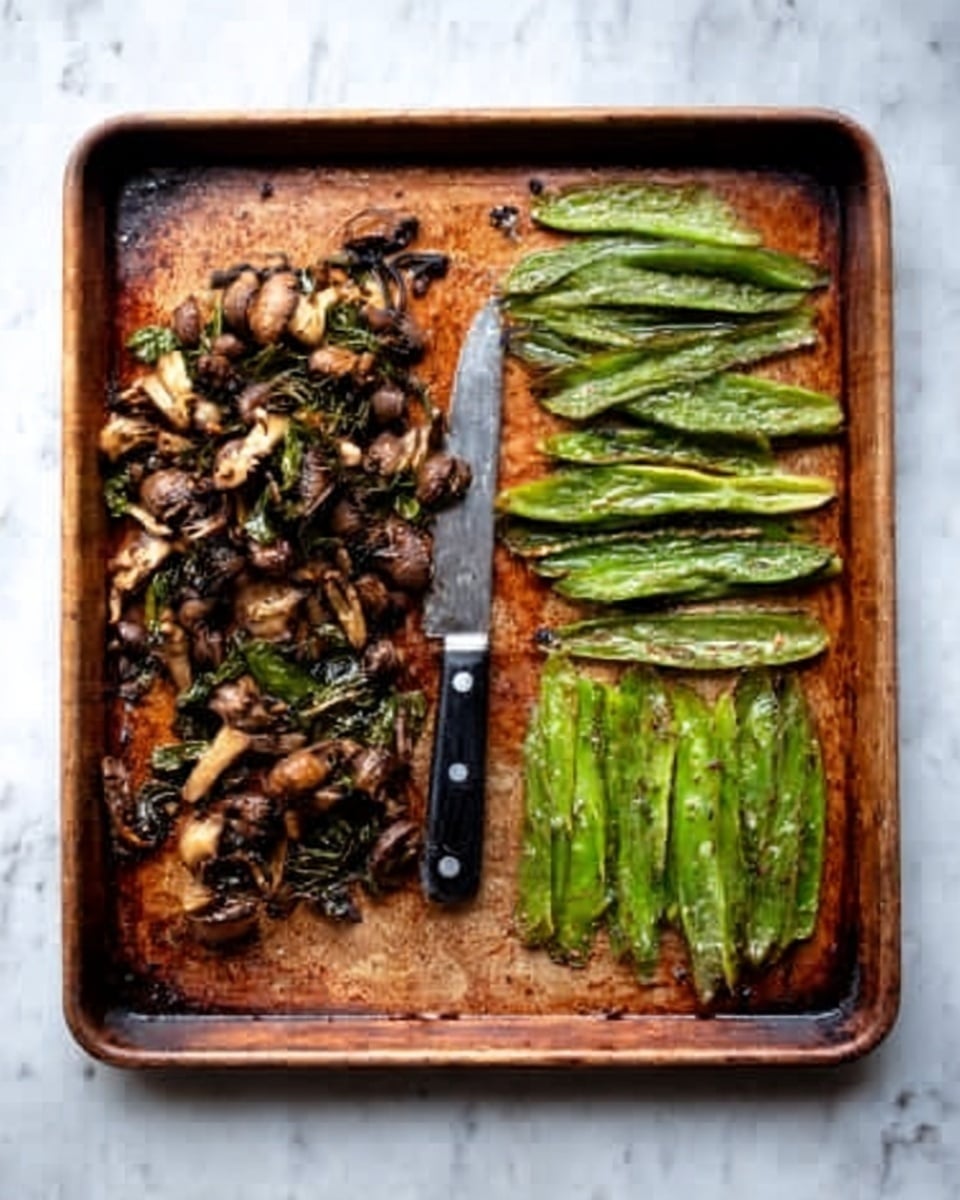 The image shows a rust-colored baking tray on a white marbled surface. On the left side of the tray, there is a messy pile of cooked chopped mushrooms with a slightly dark and wet texture. In the middle, there is a small black-handled knife with a shiny blade. On the right side, there are long, cooked green vegetable strips that look soft and slightly glossy, arranged in a neat row. The tray has some visible stains and marks from cooking. Photo taken with an iphone --ar 4:5 --v 7