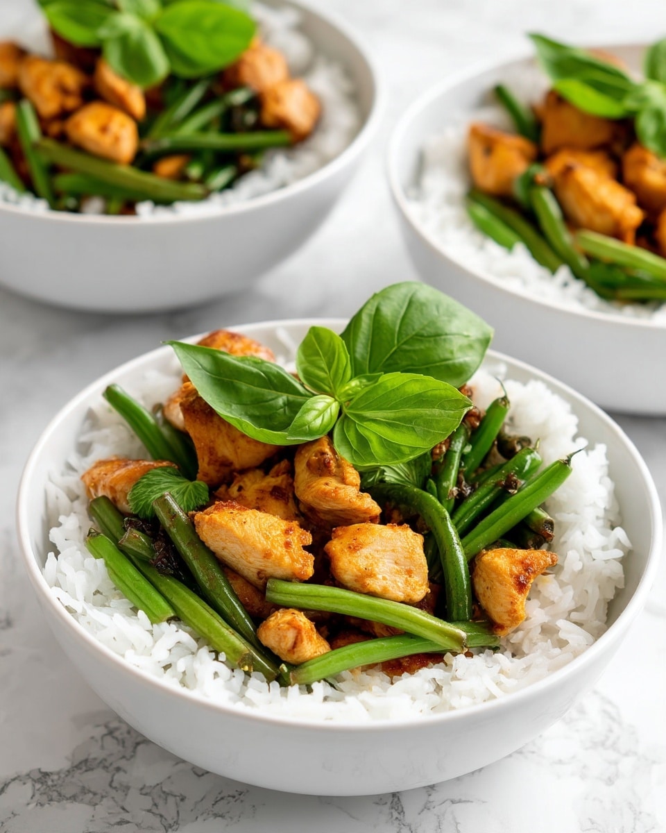 Three white bowls sit on a white marbled surface. Each bowl has two layers: the bottom layer is white rice with a soft, fluffy texture, filling most of the bowl; the top layer consists of small, golden-brown pieces of cooked chicken mixed with fresh green beans, and a few bright green basil leaves placed on top. The chicken pieces have a slightly crispy outside and a warm, cooked color. The bowls are arranged with one closer to the front and two slightly behind. Photo taken with an iphone --ar 4:5 --v 7